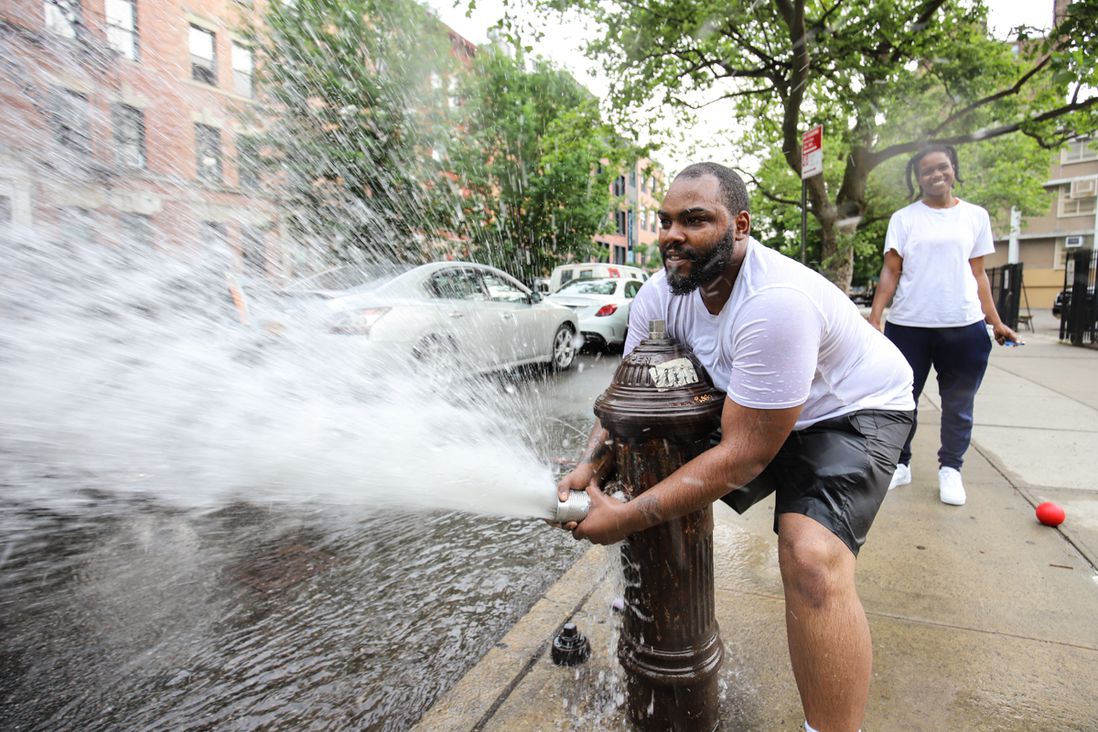 A photo of a man opening a fire hydrant in Crown Heights